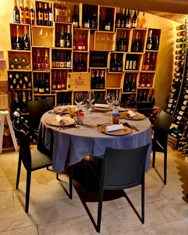 Il tavolo apparecchiato nella sala privata, circondato dalle bottiglie dell'enoteca del Bistrot del Portico